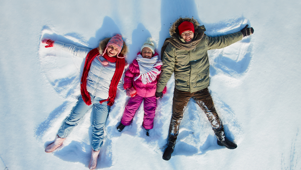 Father mother and daughter make a family snow angel