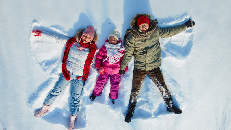 Father mother and daughter make a family snow angel