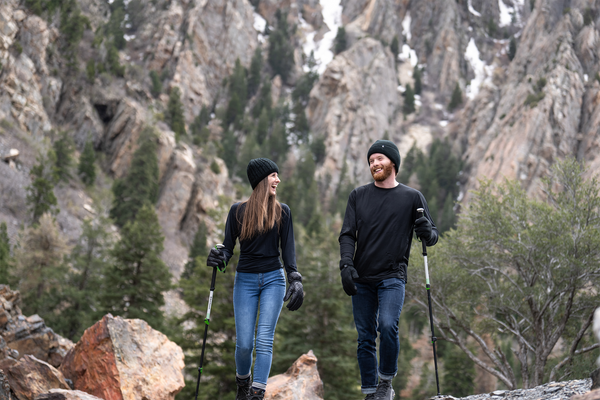 Man and woman hiking in the mountains wearhing Heat Holders® hiking gear