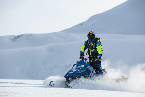 Person on snowmobile travelling over snowy landscape. Heat Holders® Base Layers