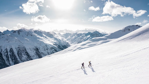 Two people hiking on a snow covered mountain