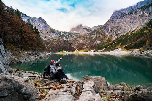 Woman and man sitting beside a lake while on a cold hike. | Heat Holders®