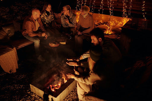 A group of friends sits around a fire on a cold evening. | Heat Holders®