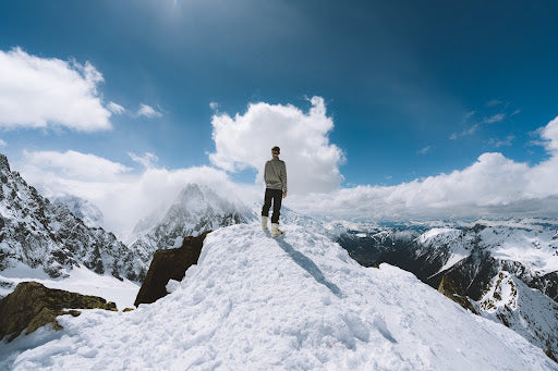 Man stands on a peak looking out over a mountain range. | Heat Holders® Base Layers