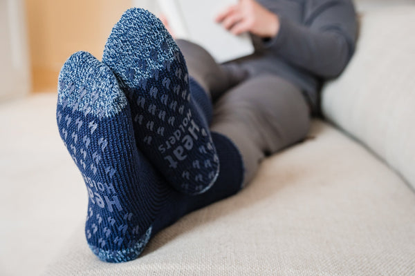 Person wearing Heat Holders® lounge socks, slipper socks relaxes while they read.