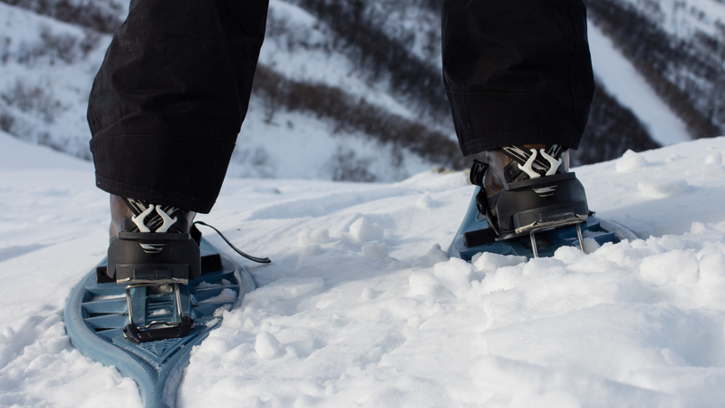 A person walking away on a pair of high tech snow shoes.