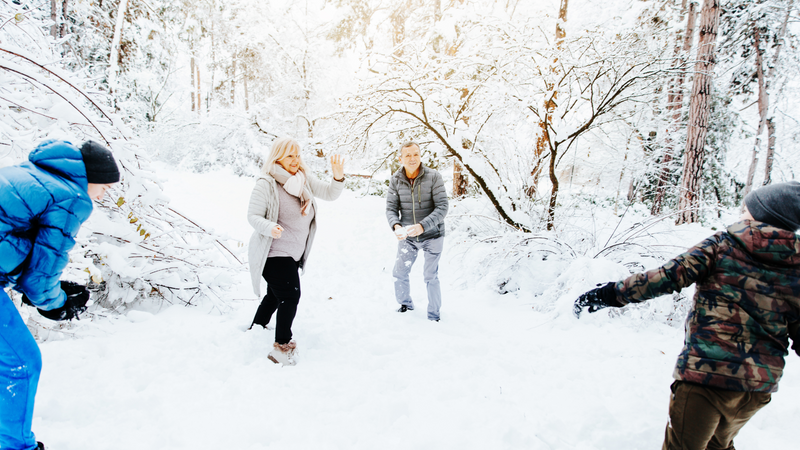 Two older women have a snowball fight with two kids
