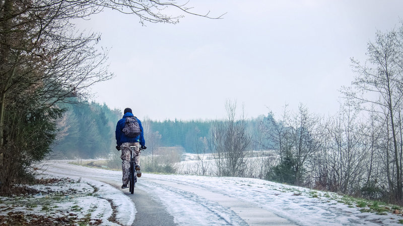 A man cycles down a country road in winter. | Heat Holders®