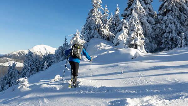  Person with hiking gear climbing a snowy hill