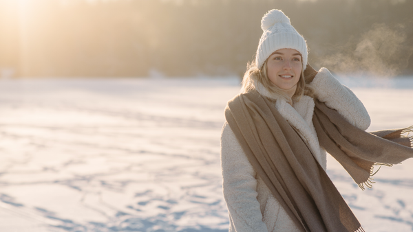 Woman wearing a fleece beanie outdoors enjoying the sunny winter weather.