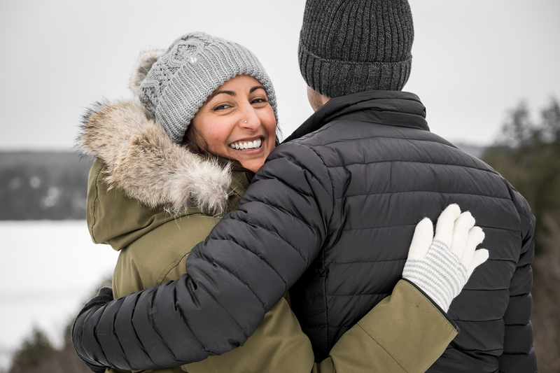 Smiling woman hugging man looks back while on a hike. | Heat Holders®
