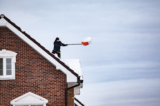 Man shovels snow off of his roof. Heat Holders® WORXX socks
