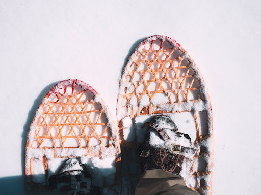 Looking down at the top of snow shoes and feet on the snow.  | Heat Holders®