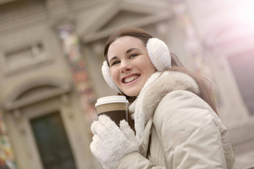 Woman Smiling Drinking Coffee and Wearing White Earmuffs