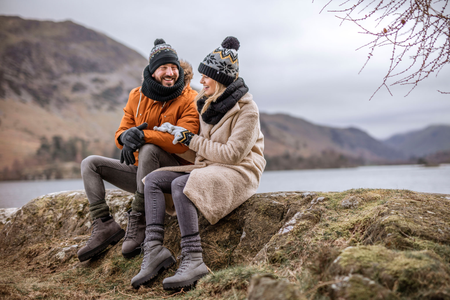 Couple wearing Heat Holders thermal socks and accessories sitting beside a lake