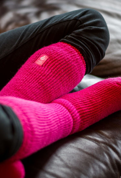 Heat Holders Banner with warm pink Original socks warm and cozy on a muskoka couch 